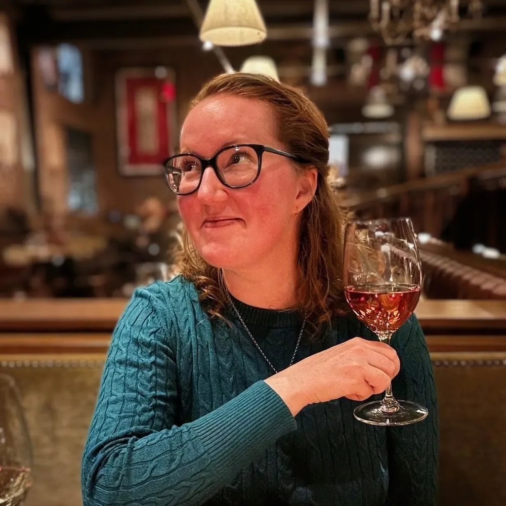 Mairéad smiling and holding a glass of wine at a cozy restaurant table