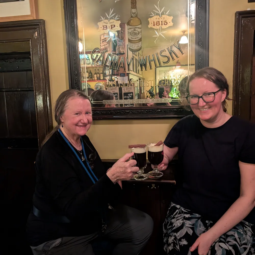 Mairéad and her mom raising glasses of Irish coffee in a pub